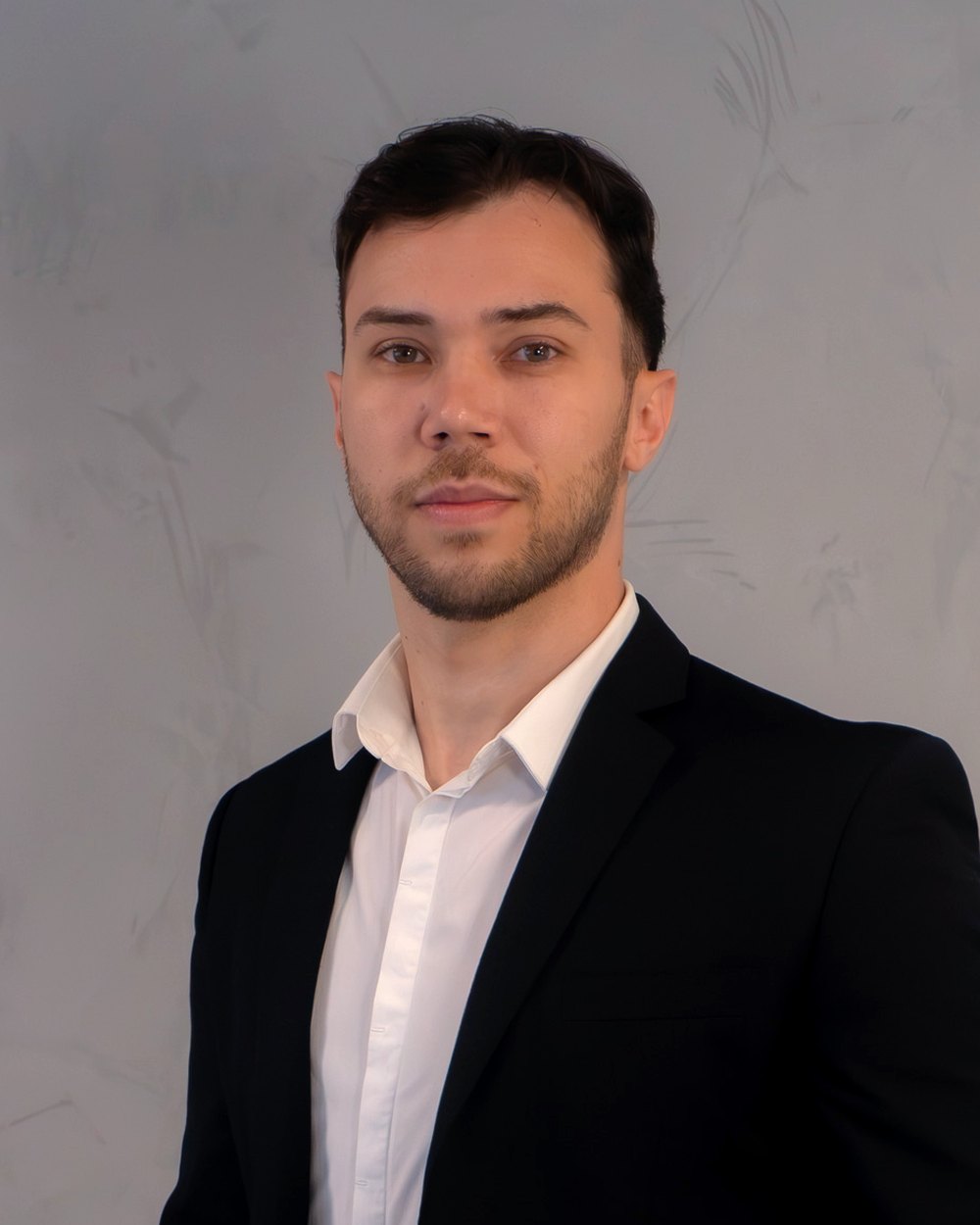 Carlos Cardoso, assessor de investimentos do Grupo Brunello, de terno preto em frente a uma parede clara.