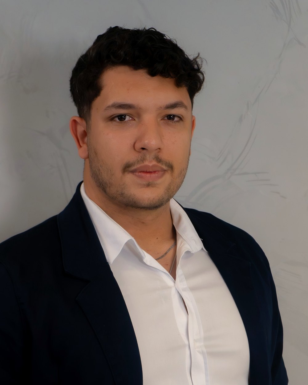 João Rovari, head de crédito imobiliário do Grupo Brunello, de terno azul-marinho em frente a uma parede clara.