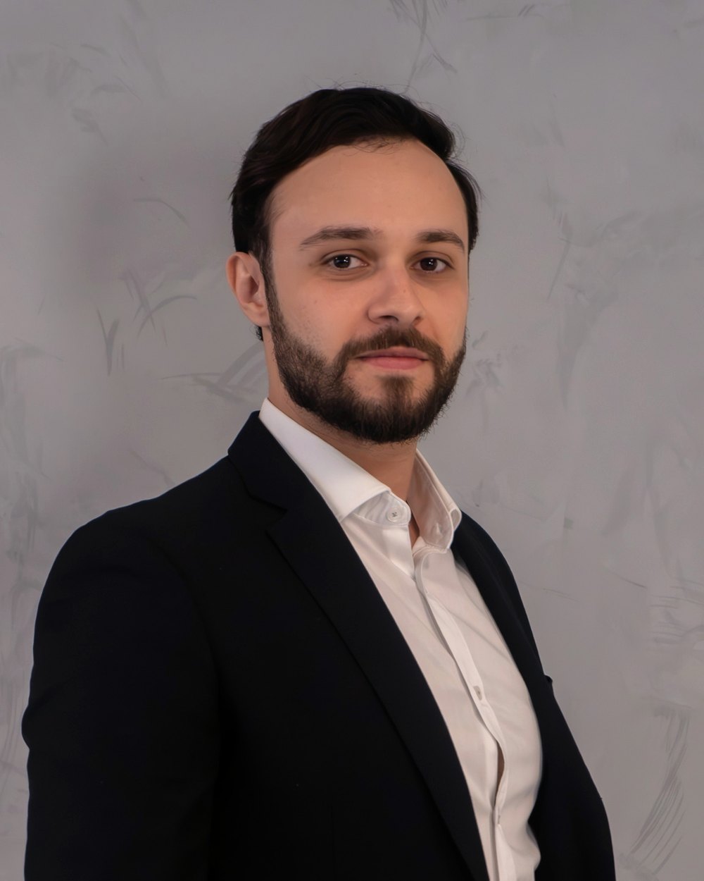 Leandro Alves, head de soluções patrimoniais do Grupo Brunello, de terno preto em frente a uma parede clara.