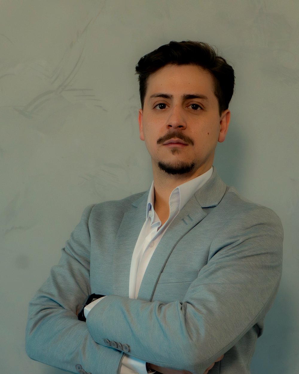 Ricardo Lima, assessor de investimentos do Grupo Brunello, de terno cinza-claro em frente a uma parede clara.